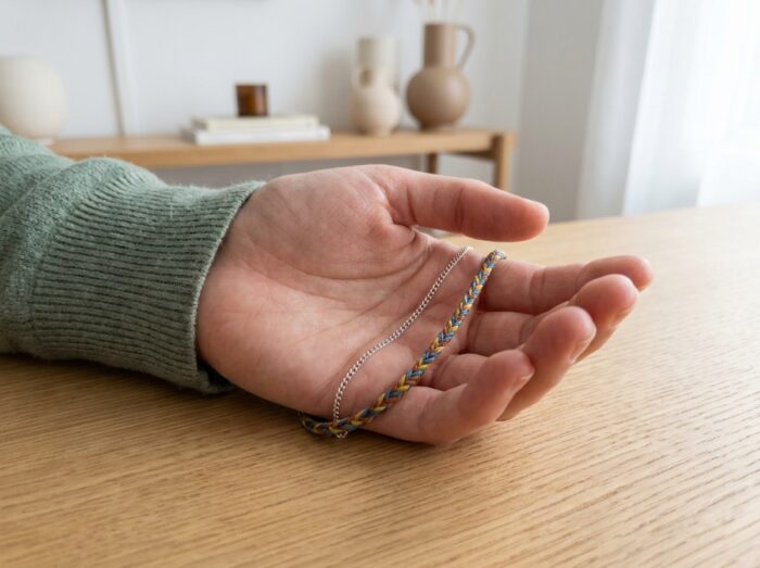 Femme tenant un bracelet fin en argent et un cordon tressé coloré dans la paume pour les comparer